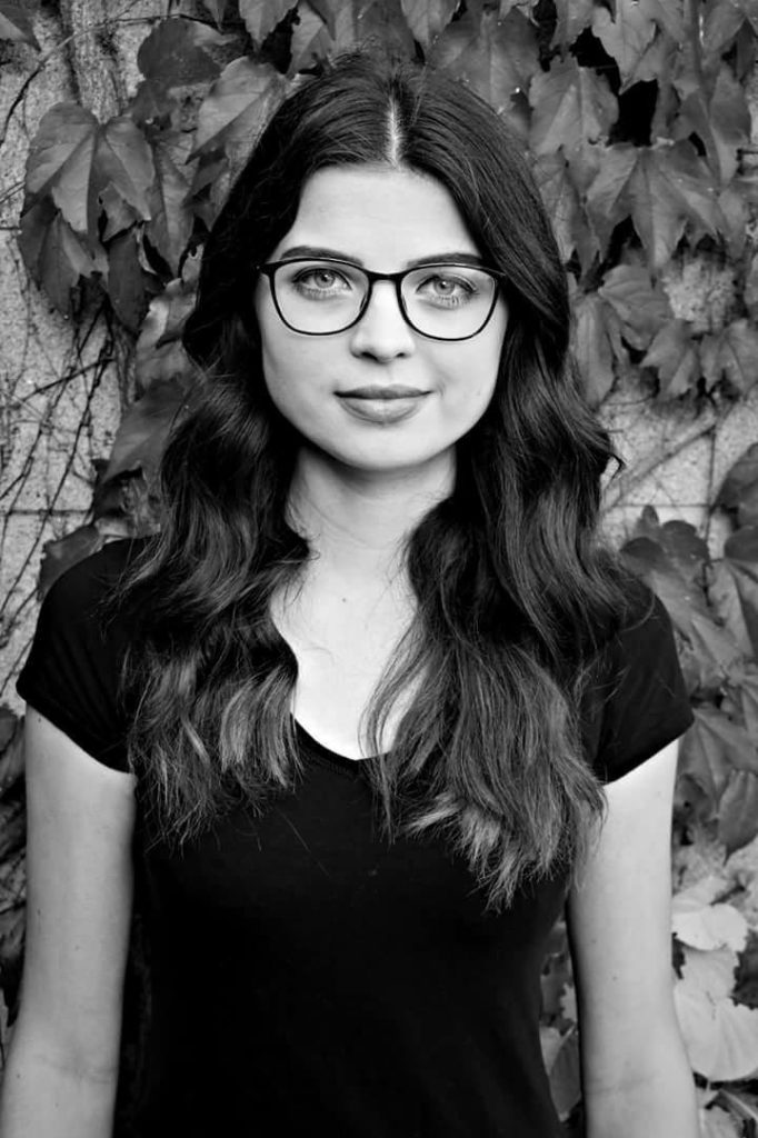 A black and white photo of Jenni, up close. She is wearing a black top and glasses. 