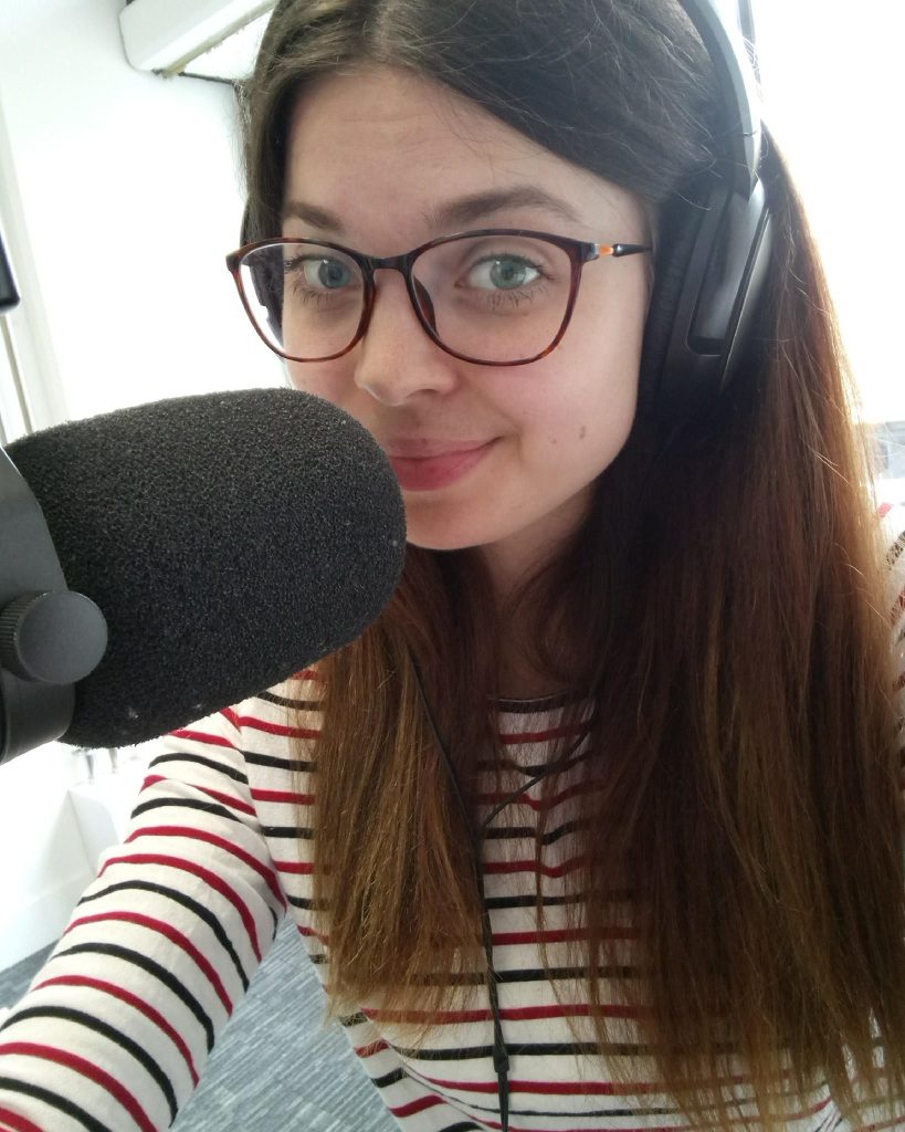 Jenni sat in front of a microphone, wearing headphones and a stripe top.