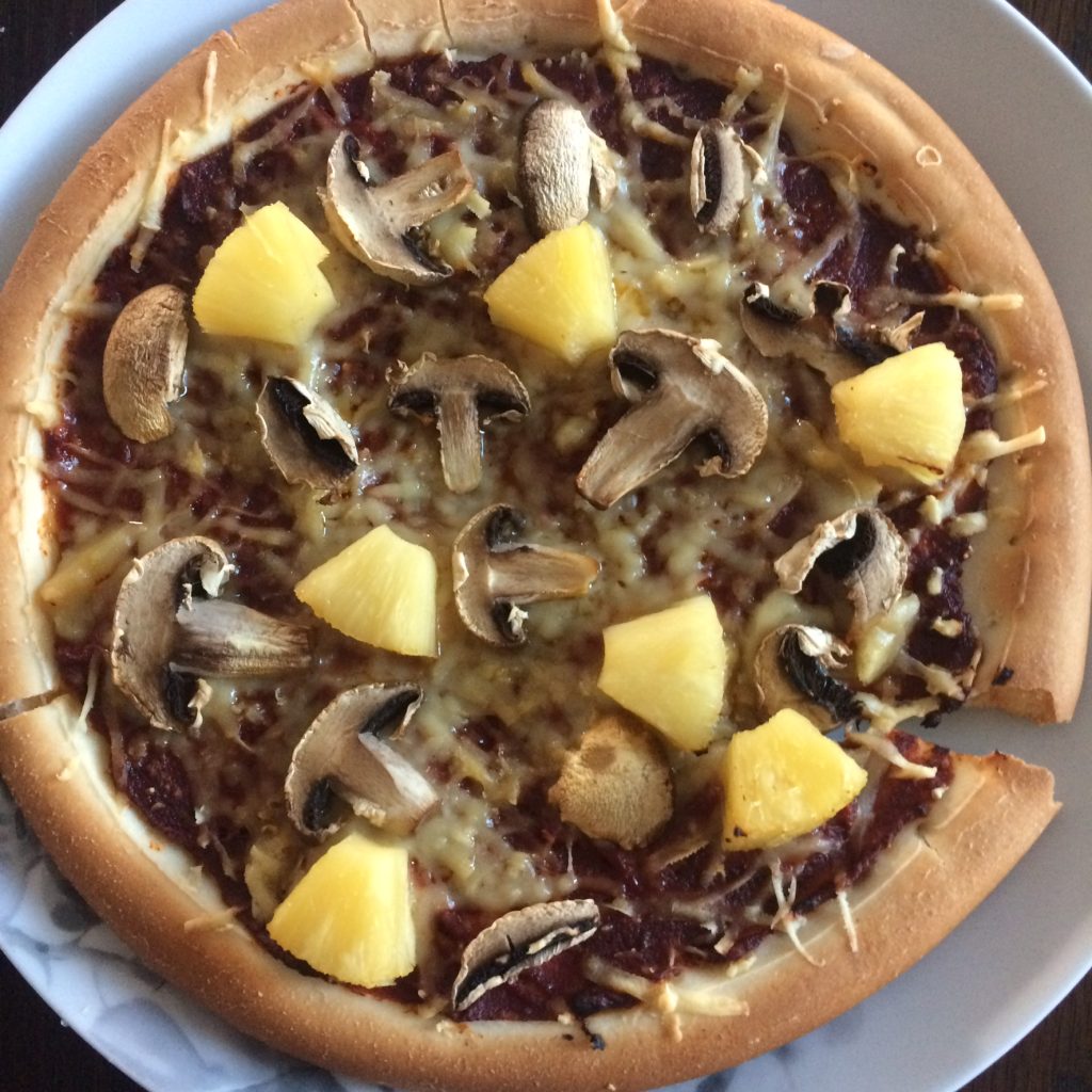 A pizza covered in mushrooms, cheese and pineapple.