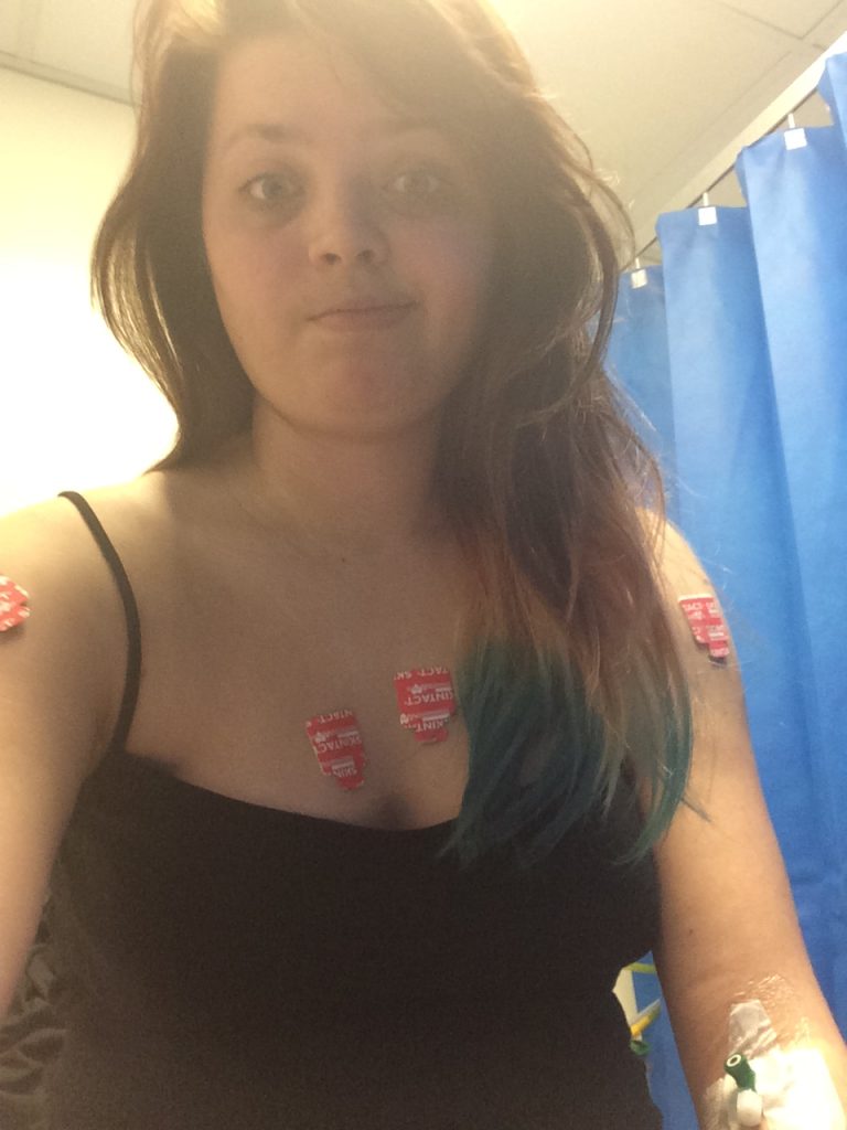 Jenni in a hospital environment, covered in electrodes, wearing a black vest top.