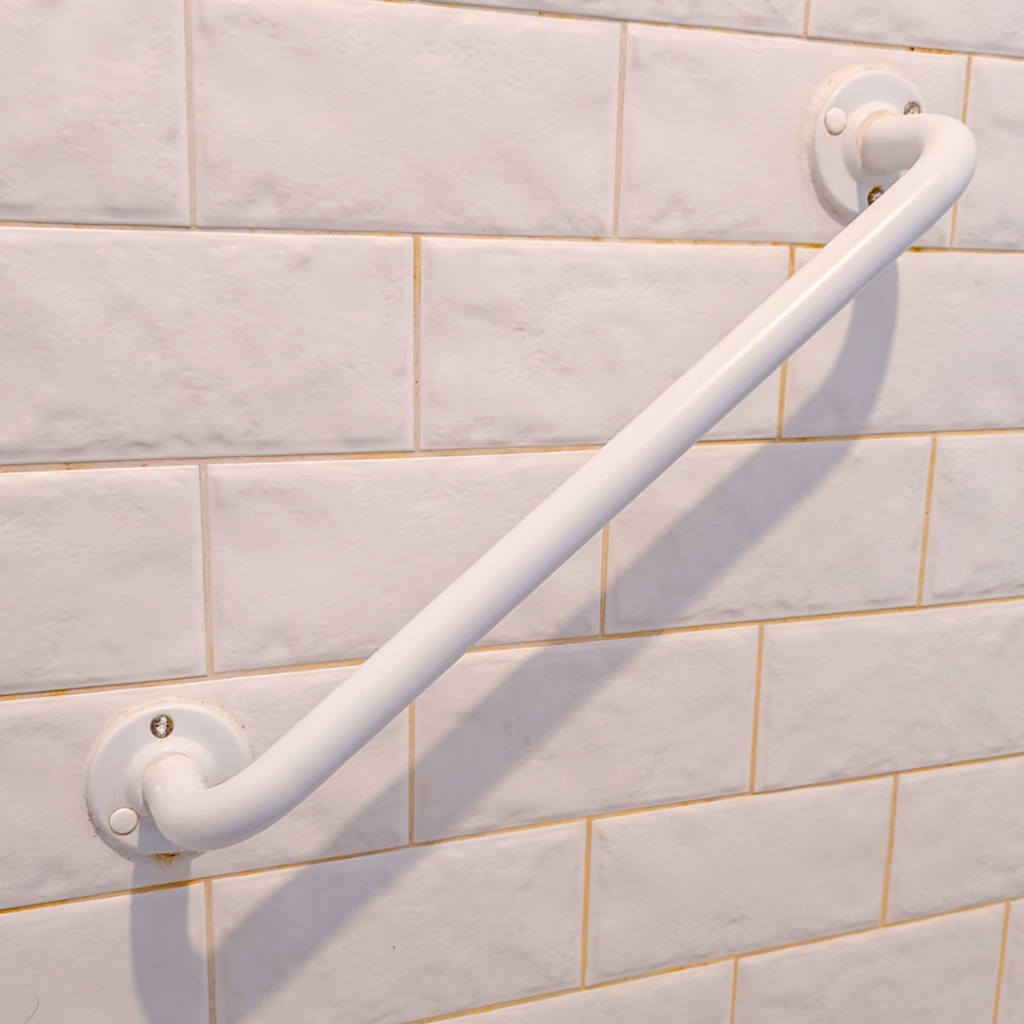 A white grab rail on a tiled wall