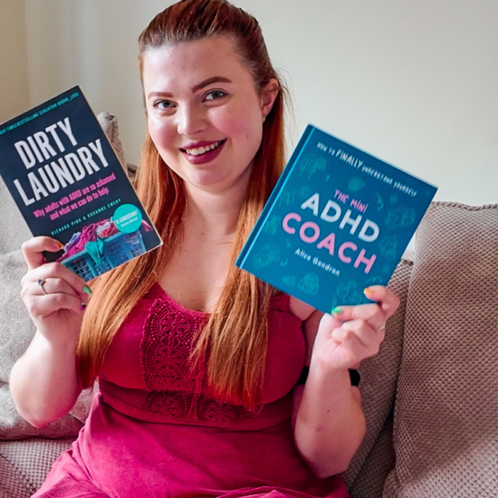 Jenni holding two books in the air, smiling.