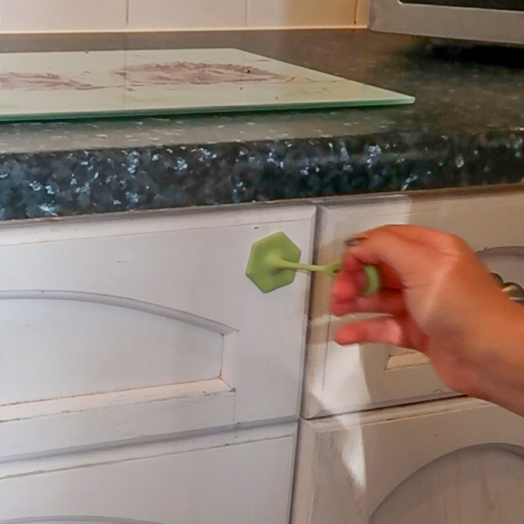 A hand using a grip pull on a cupboard