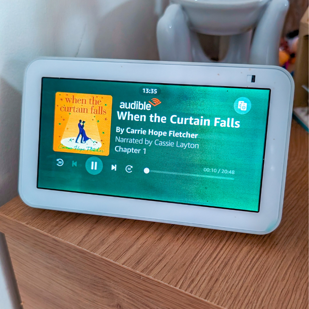 A close-up of an Amazon Echo Show with an audiobook playing