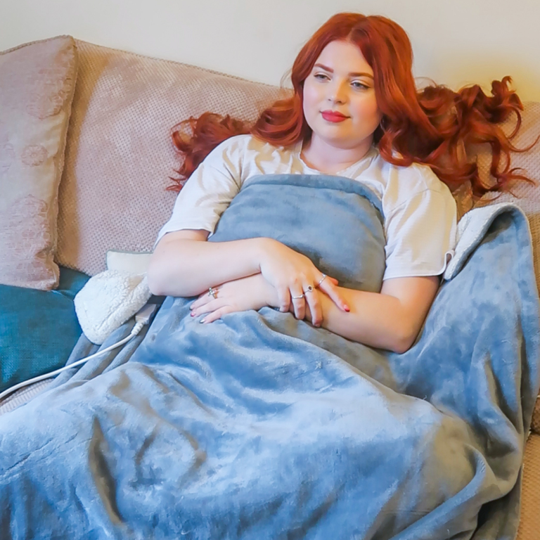 Jenni laying on the sofa under a weighted blanket.