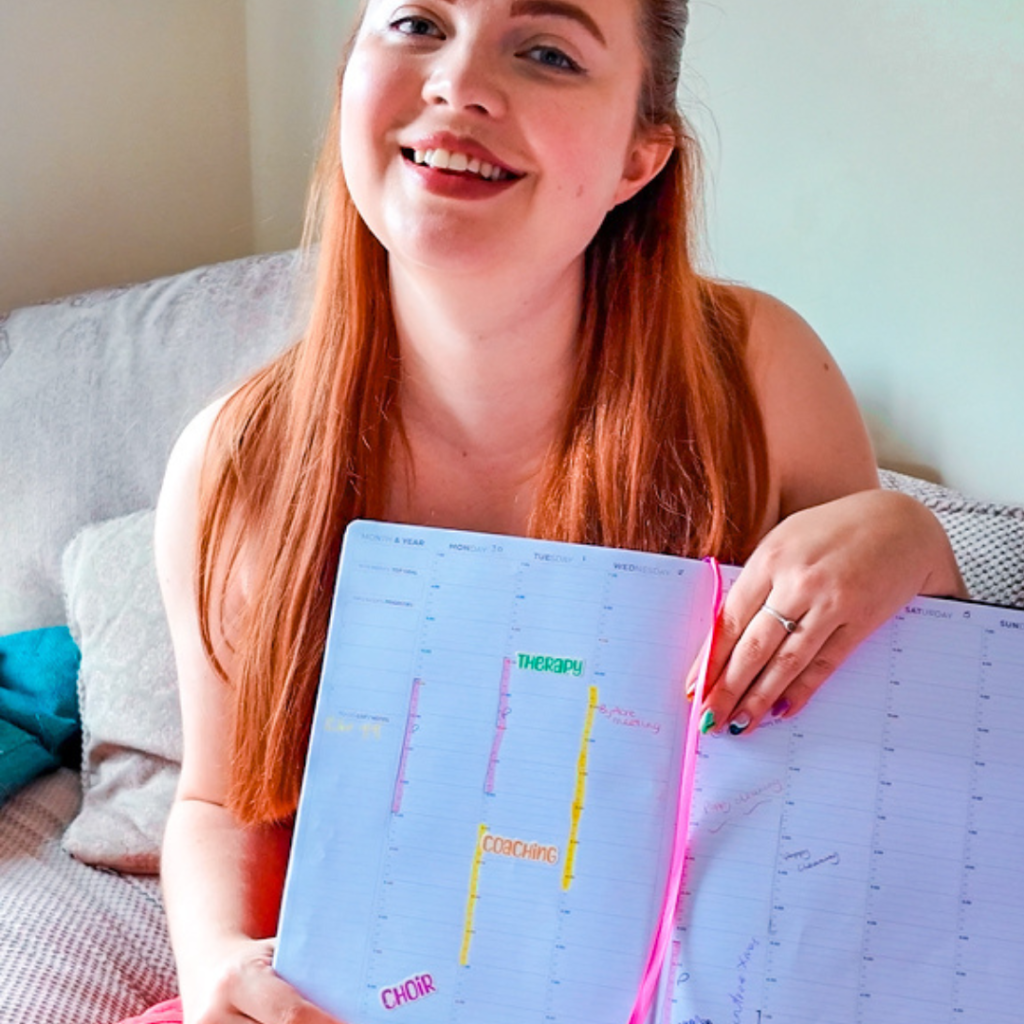 Jenni holding a diary in hand with notes, smiling.