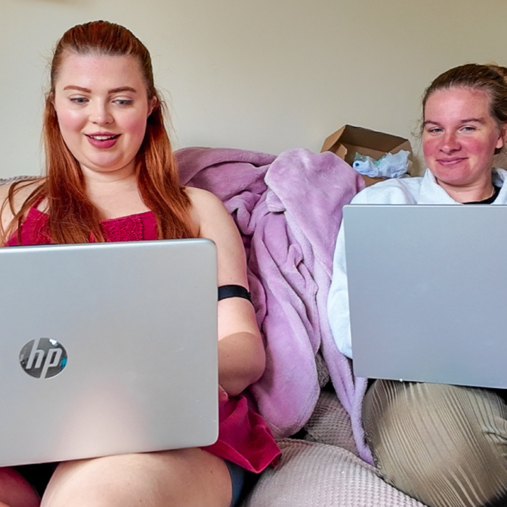 Jenni working on the sofa with Poppy, both using their laptops.