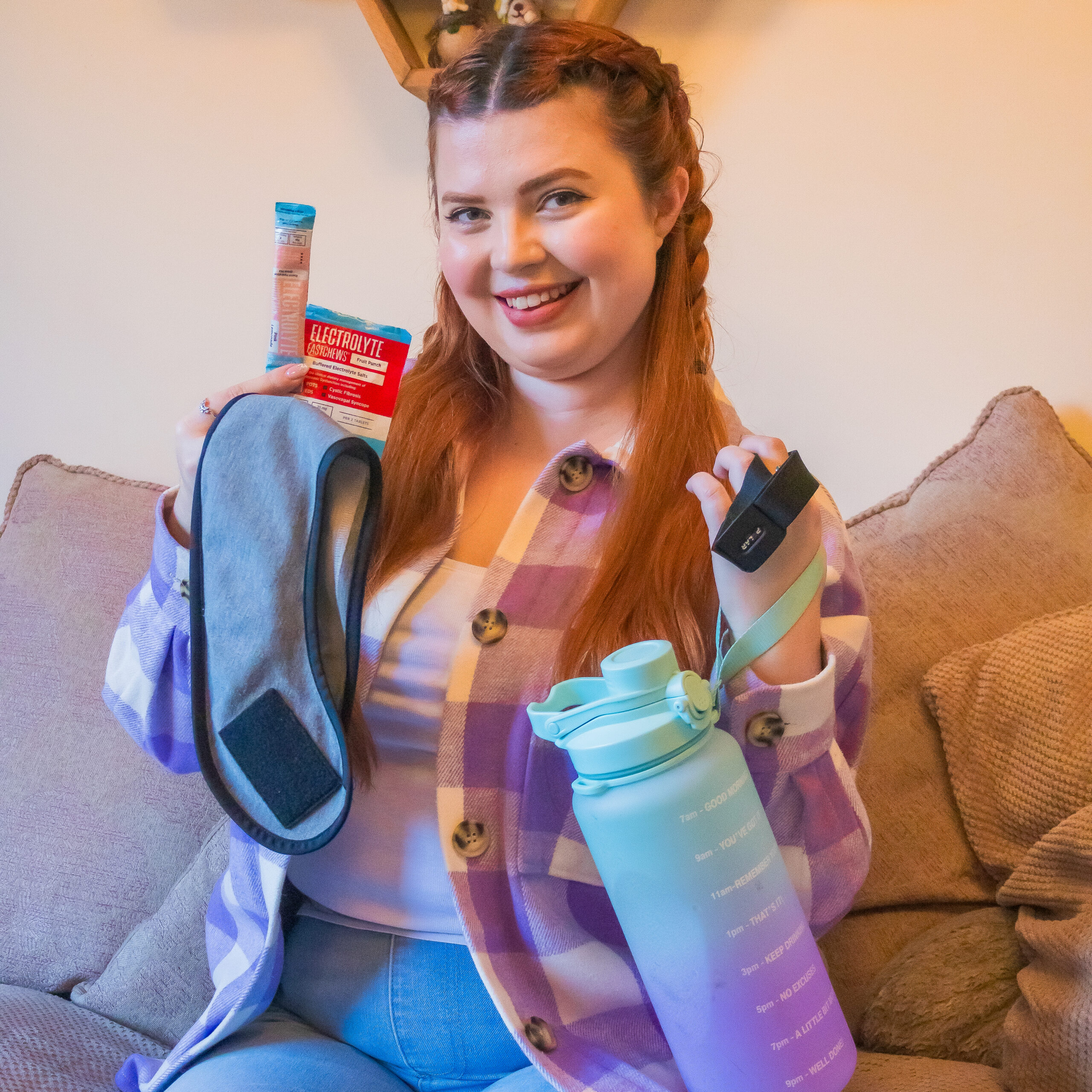 Jenni sat on the sofa, holding various hack tools for managing POTS