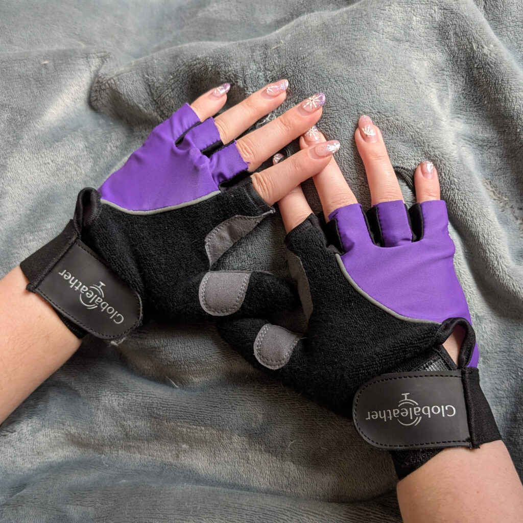 Jenni's hands wearing purple wheelchair gloves which are fingerless but with a covered thumb