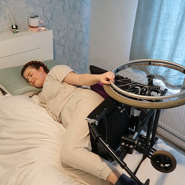 Jenni laying in bed whilst also sat in her manual wheelchair which is laying on its side in bed with her. Learn more about Disability Misconceptions by reading Jenni’s article