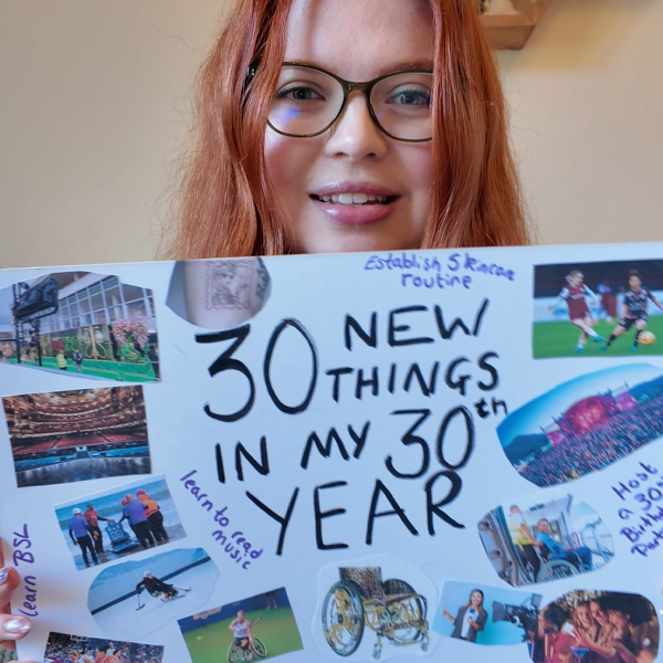 Jenni smiling holding up a sign which says '30 New Things in My 30th Year!'.