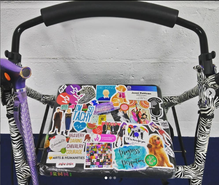 a photo of a basic rollator walker the frame is covered in zebra print tape and the seat is covered in lots of different stickers of all the things Jenni loved at the time