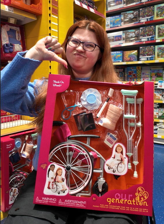 jenni doing a thumbs down whilst holding a our generation accessories set featuring a wheelchair, crutches, cast, ice pack and more.