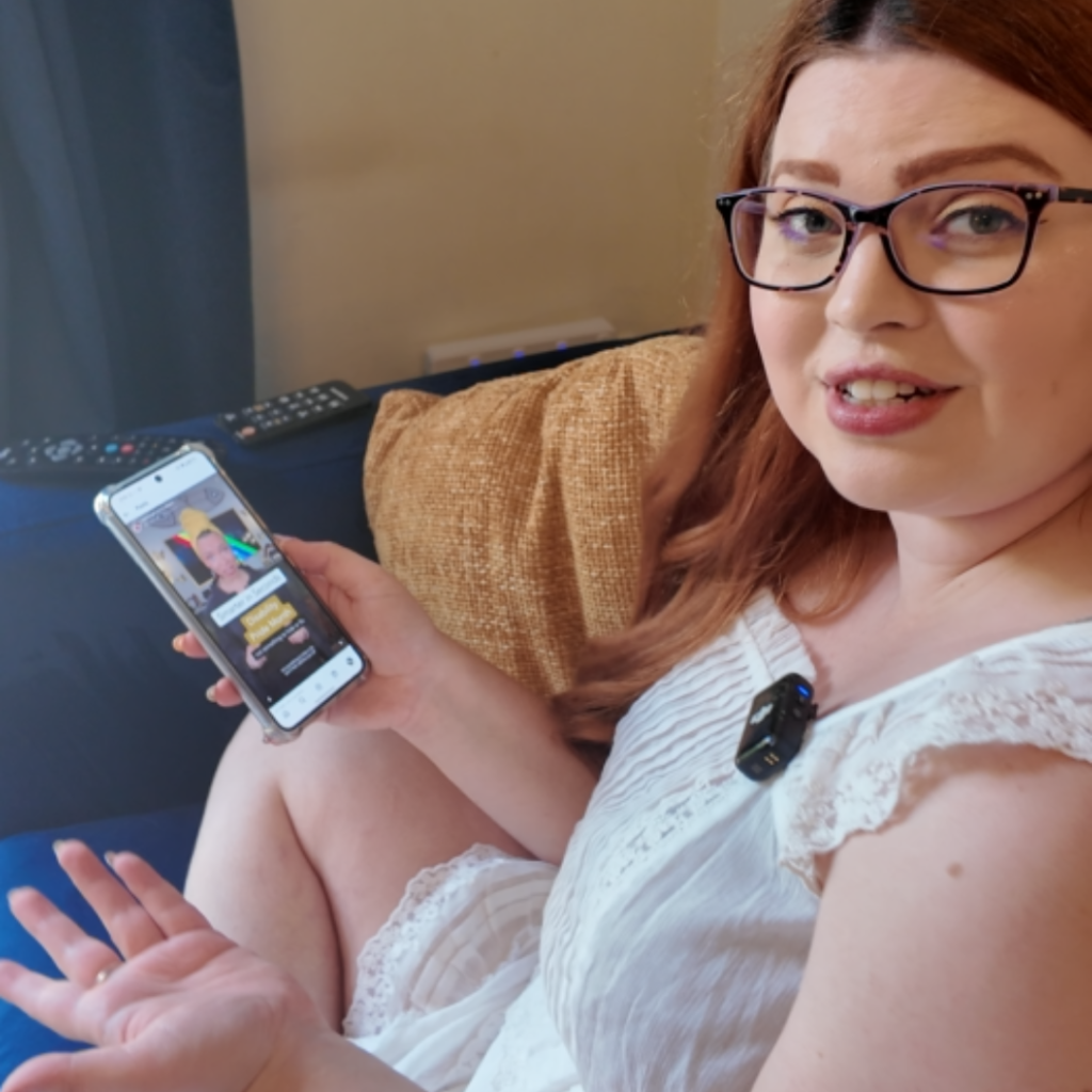 Jenni sat on her sofa holding her phone watching a video by creator Blair Imani, the video has captions on it